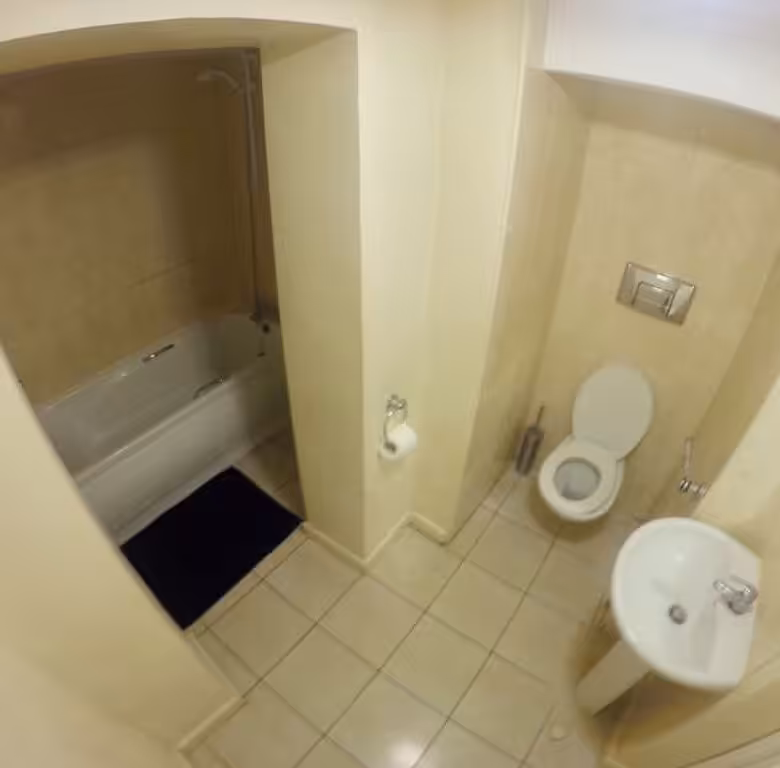 Bathroom with bathtub, toilet, sink, and beige tile.