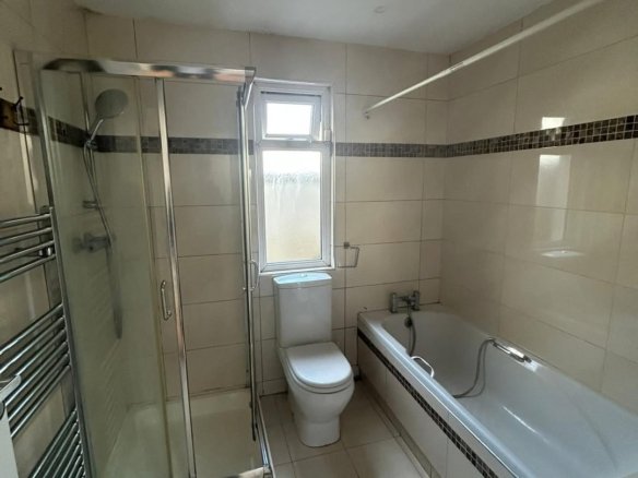 Bathroom with shower, toilet, and bathtub. Neutral tile and chrome fixtures.