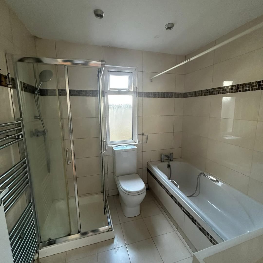 Bathroom with shower, toilet, and bathtub. Neutral tile and chrome fixtures.