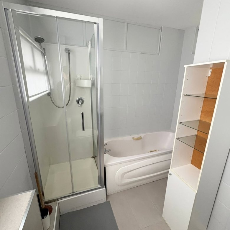 Bathroom with shower, tub, and white cabinet. Neutral color scheme.