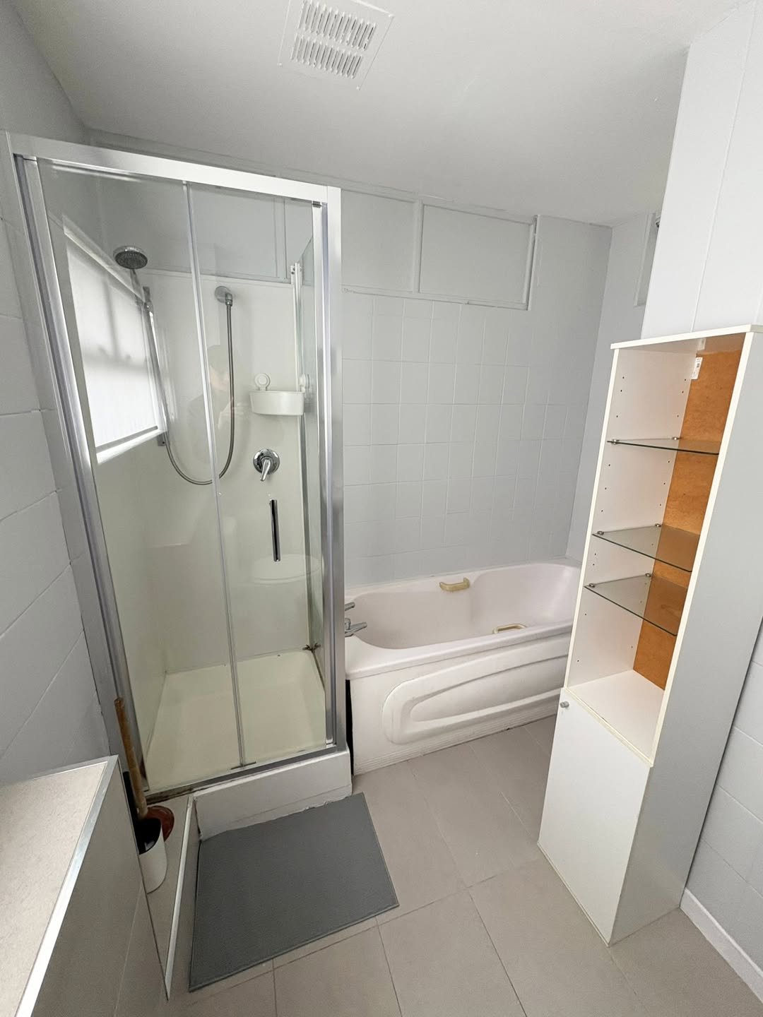 Bathroom with shower, tub, and white cabinet. Neutral color scheme.