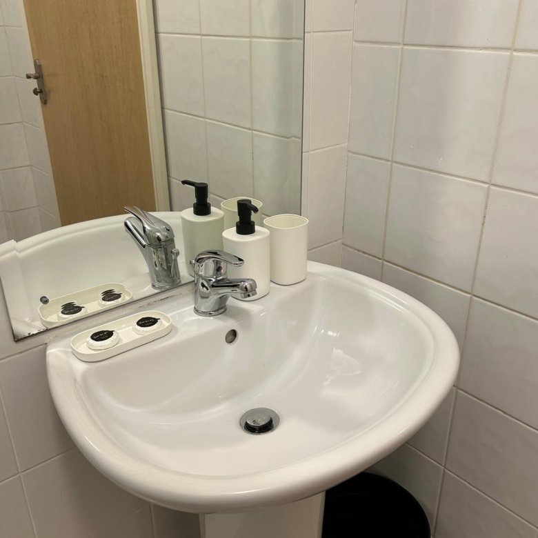 Bathroom sink with soap dispenser and toothbrush holder. White pedestal sink.
