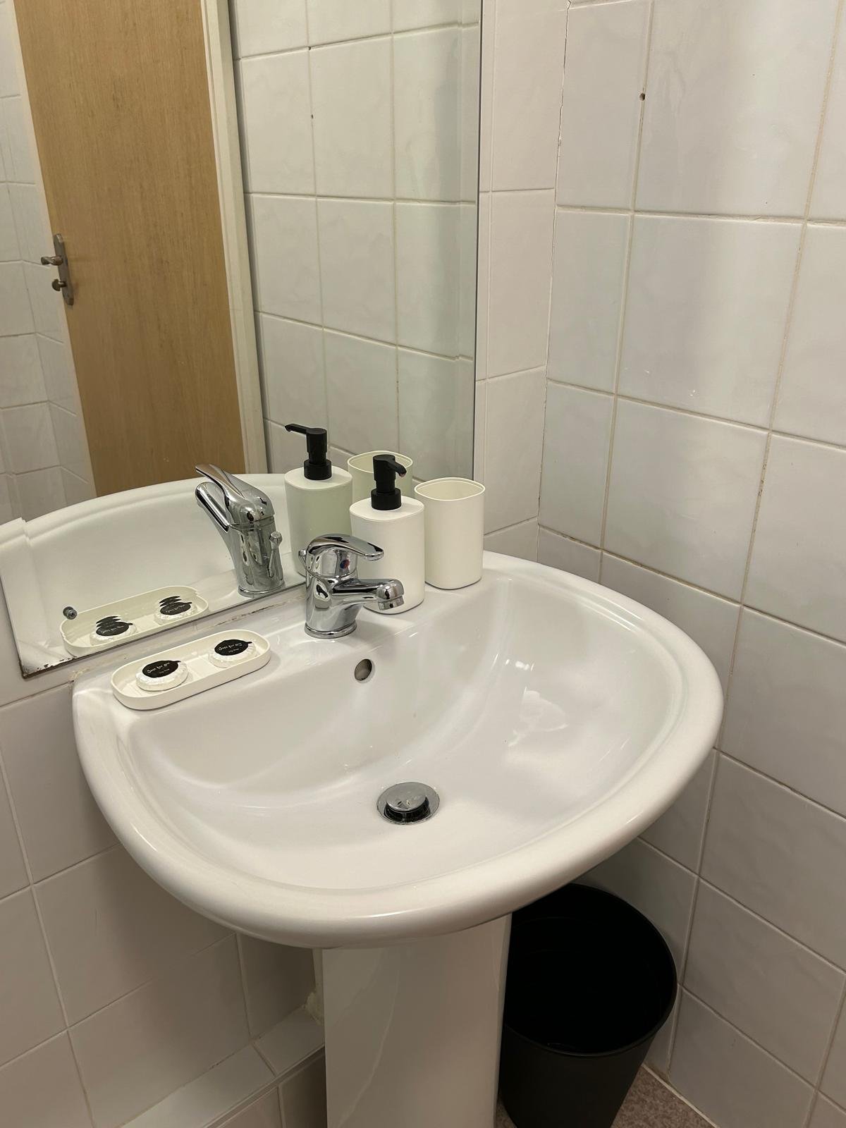 Bathroom sink with soap dispenser and toothbrush holder. White pedestal sink.
