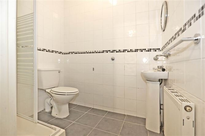 Bathroom with toilet, sink, radiator, and tiled walls.