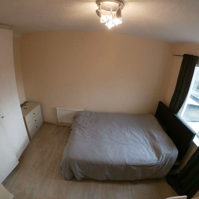 Bedroom with bed, wardrobe, dresser, and window with curtains.