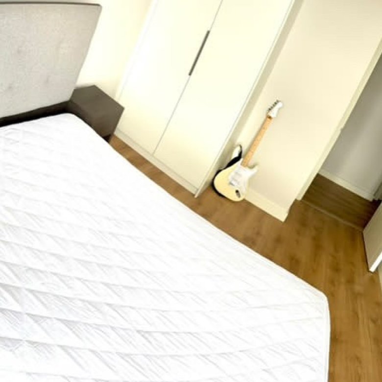 Bedroom with bed, wardrobe, and guitar. Minimalist interior design.