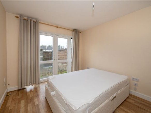 Bedroom with double bed, curtains, and patio doors leading to garden.