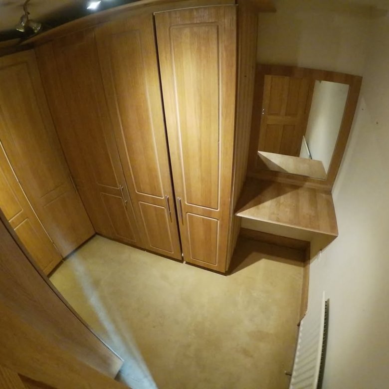 Wooden fitted wardrobes and vanity unit with mirror in bedroom.