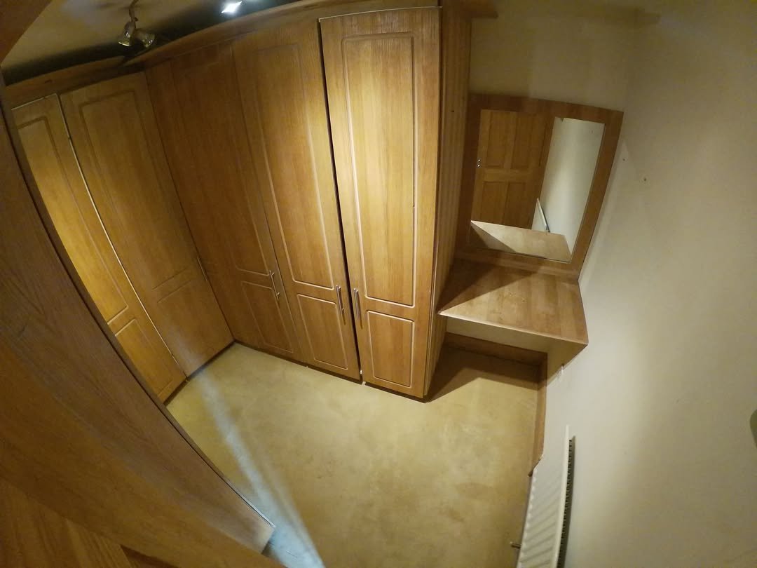 Wooden fitted wardrobes and vanity unit with mirror in bedroom.