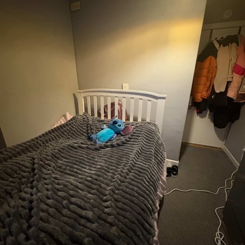 Bedroom with gray blanket on bed, Stitch plush toy, and closet.