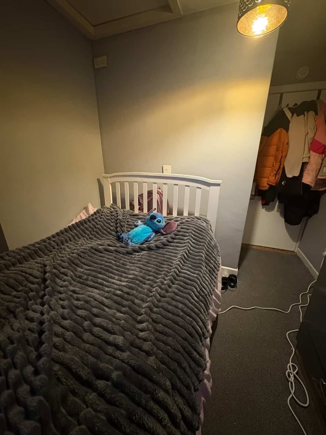 Bedroom with gray blanket on bed, Stitch plush toy, and closet.