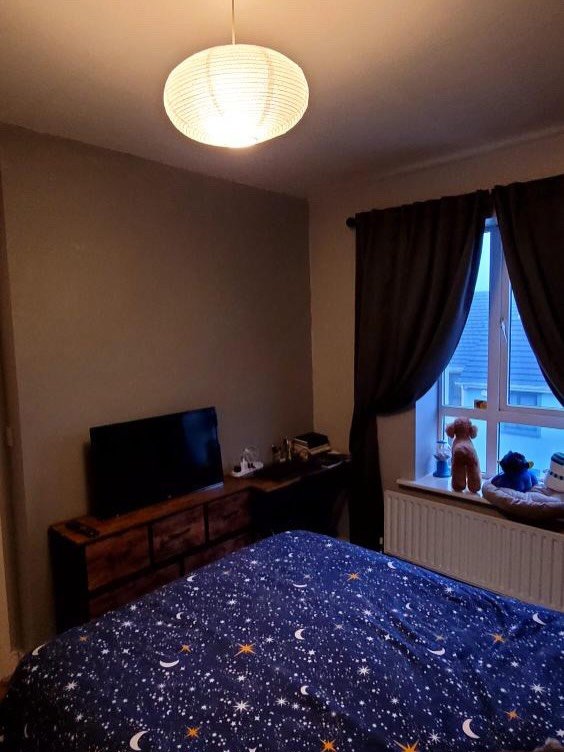 Bedroom interior with bed, TV, and window with curtains.