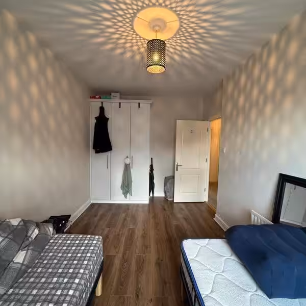 Bedroom interior with bed, wardrobe, and decorative ceiling light fixture.