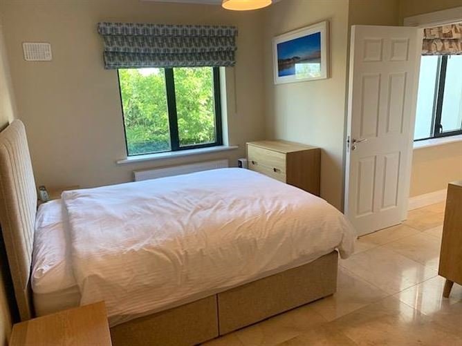 Bedroom with queen bed, window view, and small dresser. Neutral color scheme.