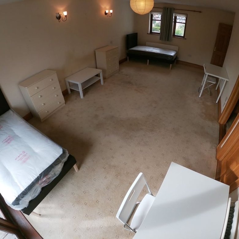 Bedroom with single bed, desk, and storage. Neutral carpet and light walls.