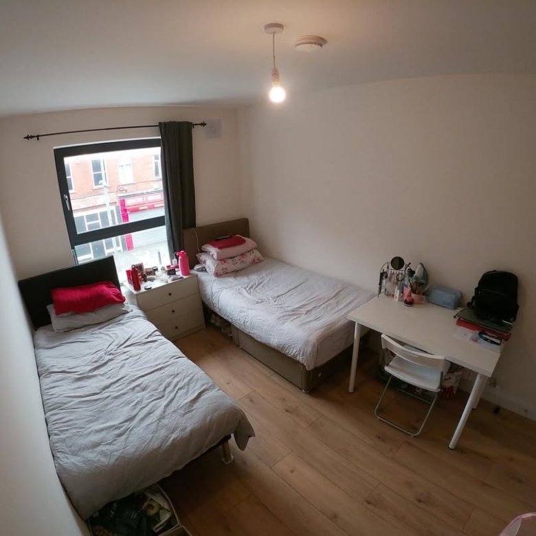 Cozy bedroom with two twin beds, desk, and window.