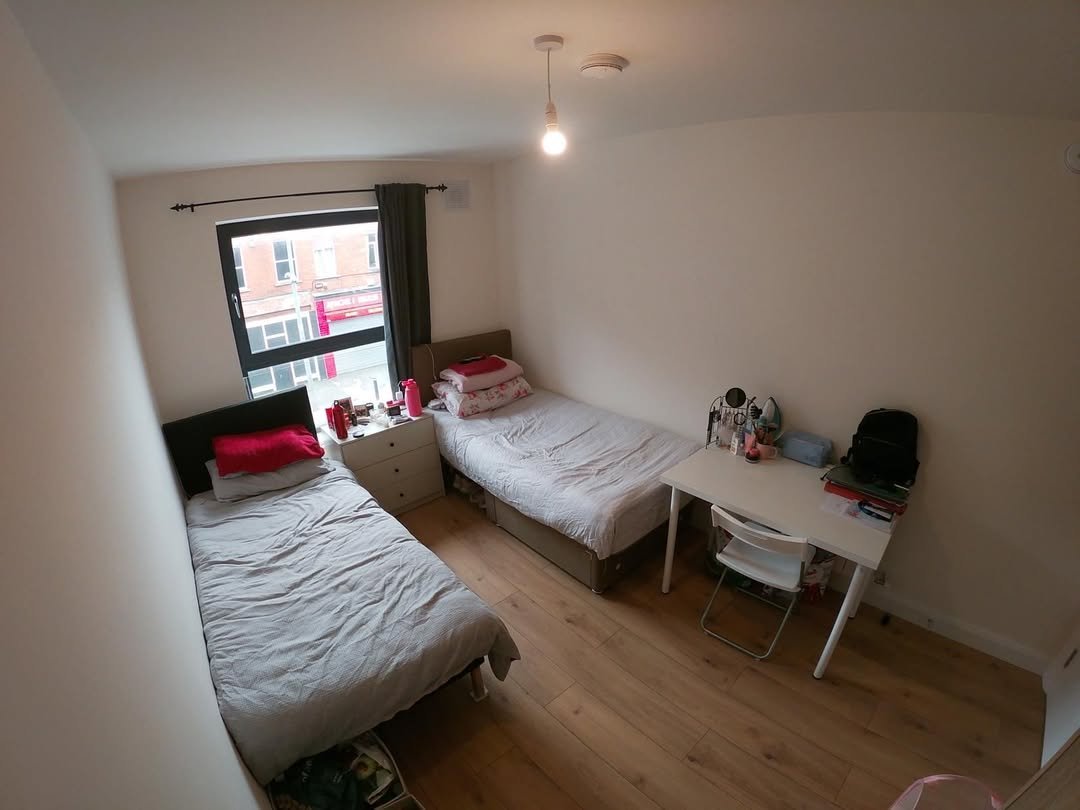 Cozy bedroom with two twin beds, desk, and window.