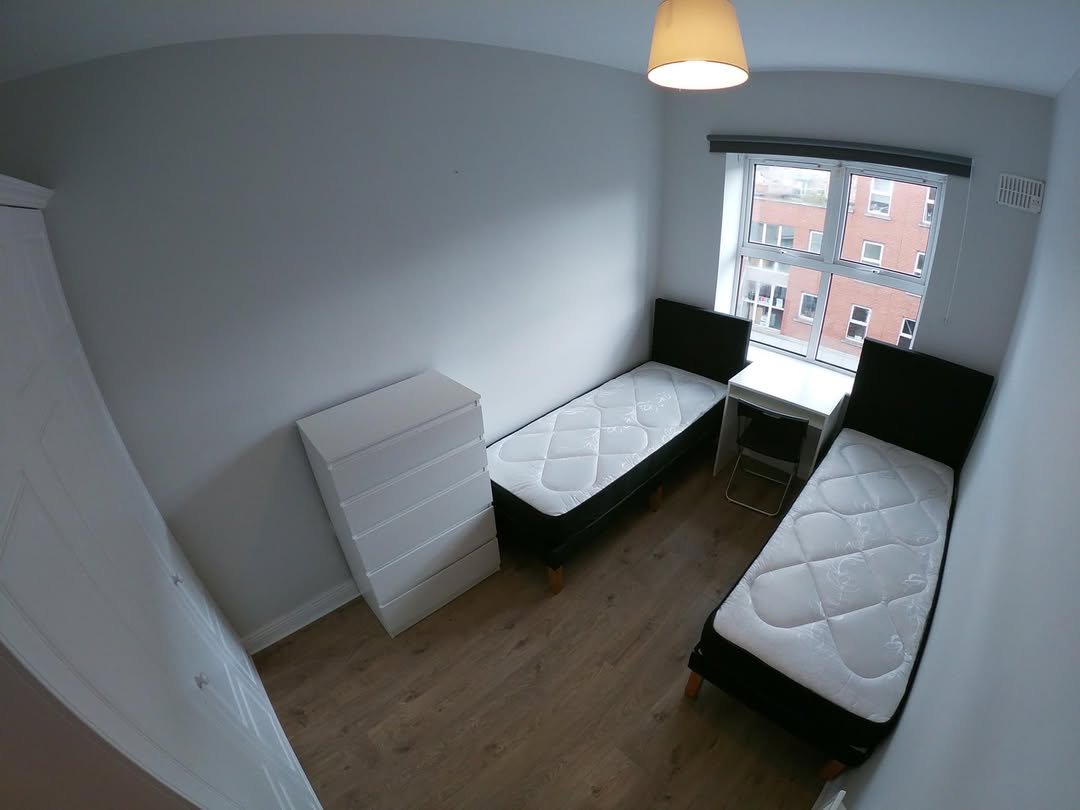 Bedroom with two twin beds, white dresser, and desk by window.