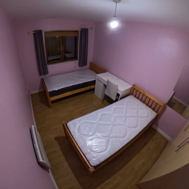 Bedroom with two single beds, desk, wardrobe, window, and pink walls.