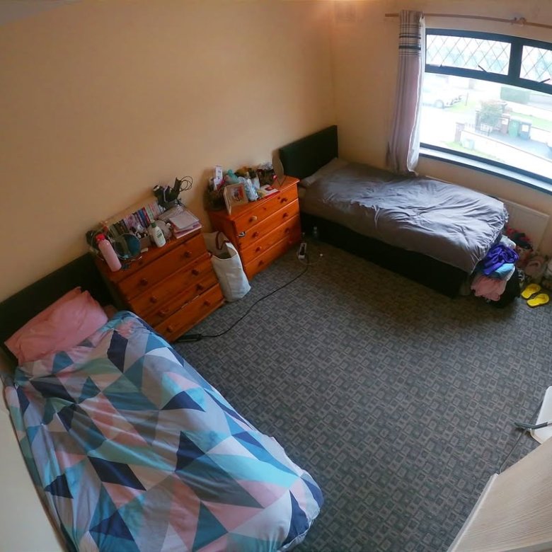 Cozy bedroom featuring two beds, wooden dressers, and a window.