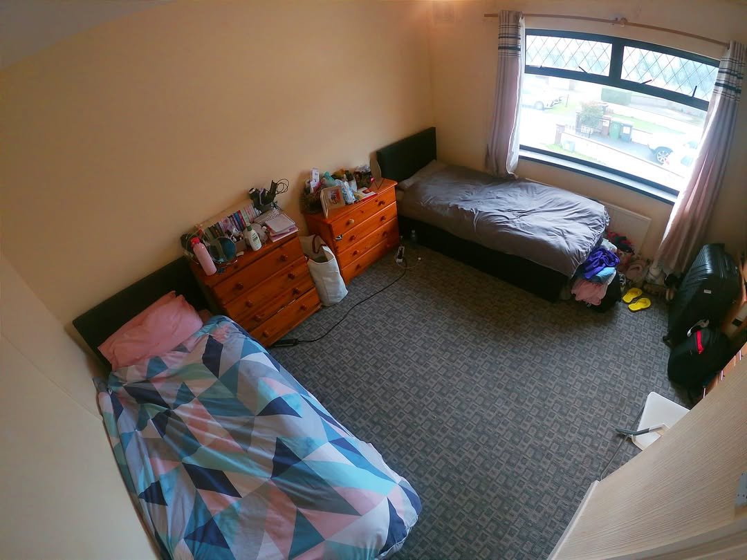 Cozy bedroom featuring two beds, wooden dressers, and a window.
