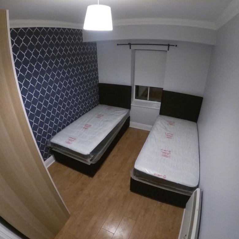 Bedroom with two single beds, blue wallpaper, and wood flooring.