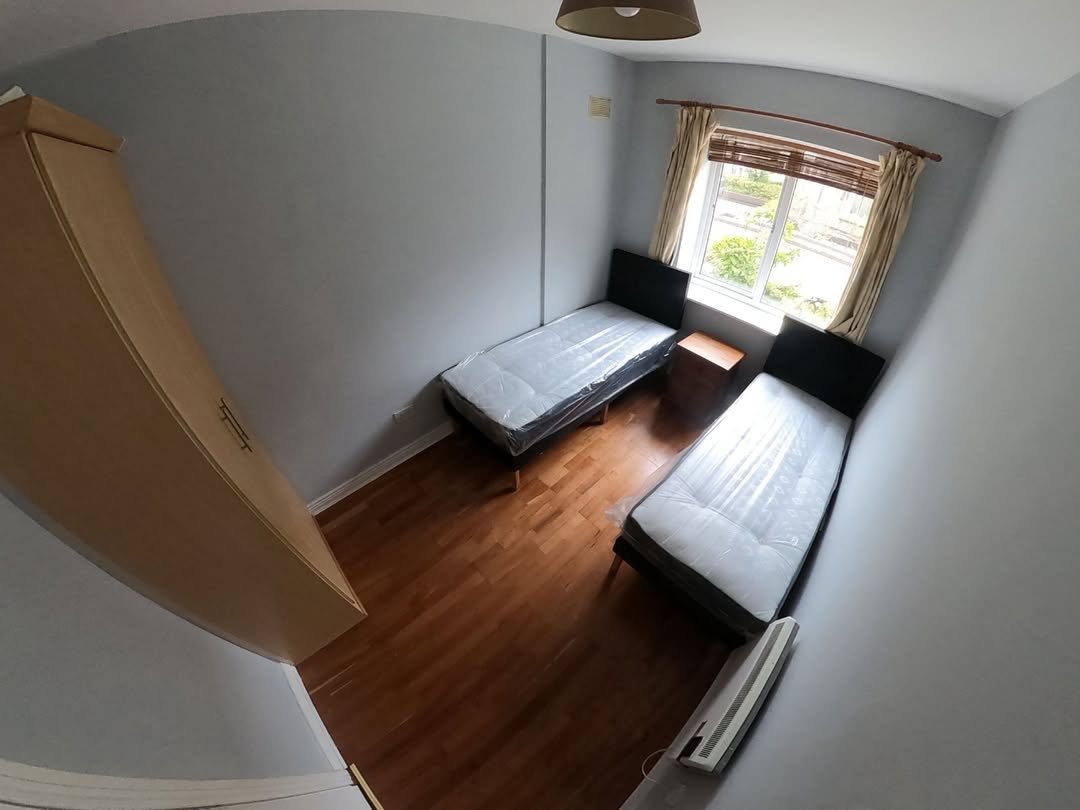 Bedroom with two single beds, wardrobe, and window.