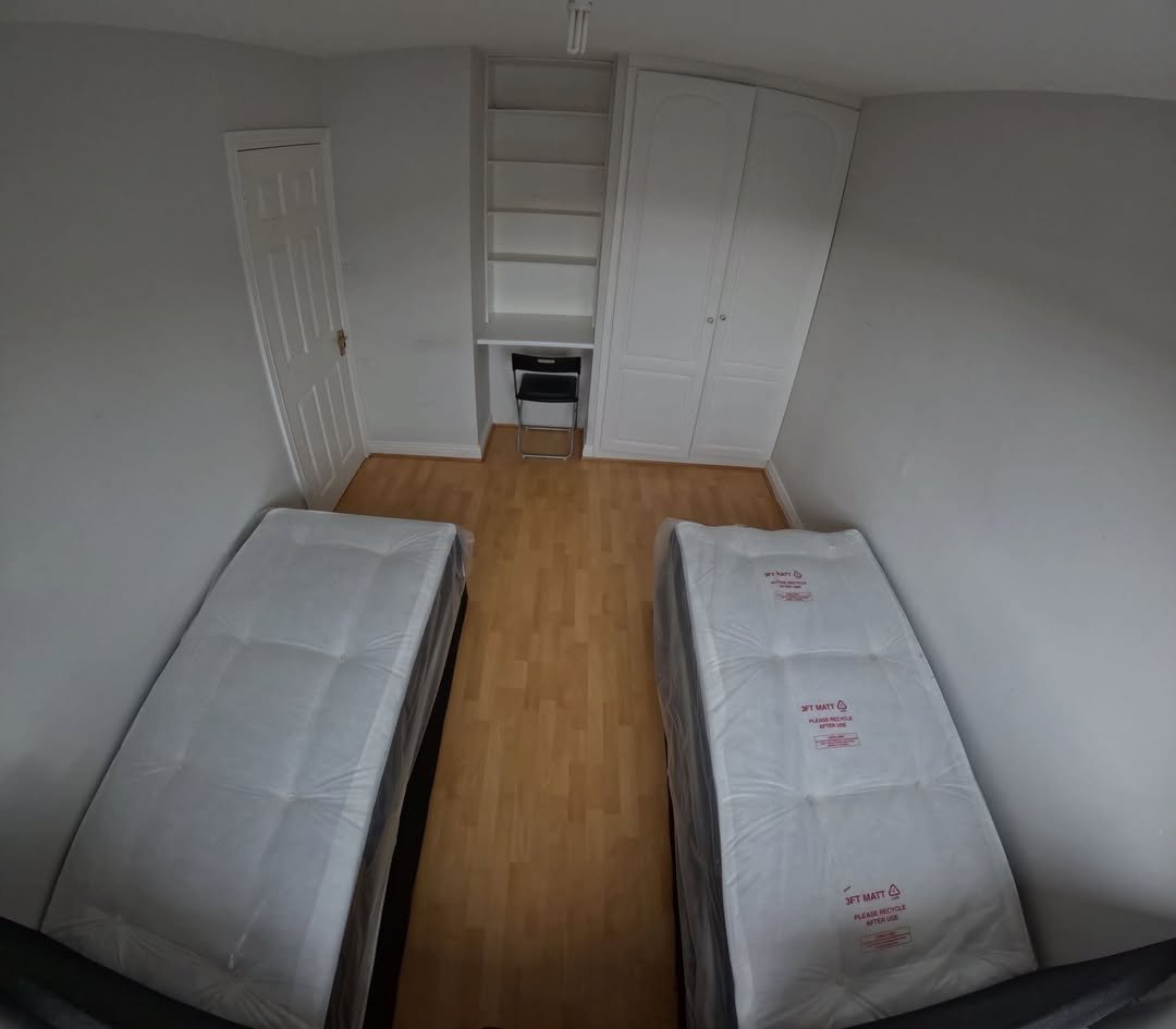 Bedroom with two single beds, built-in wardrobe, and small desk area.