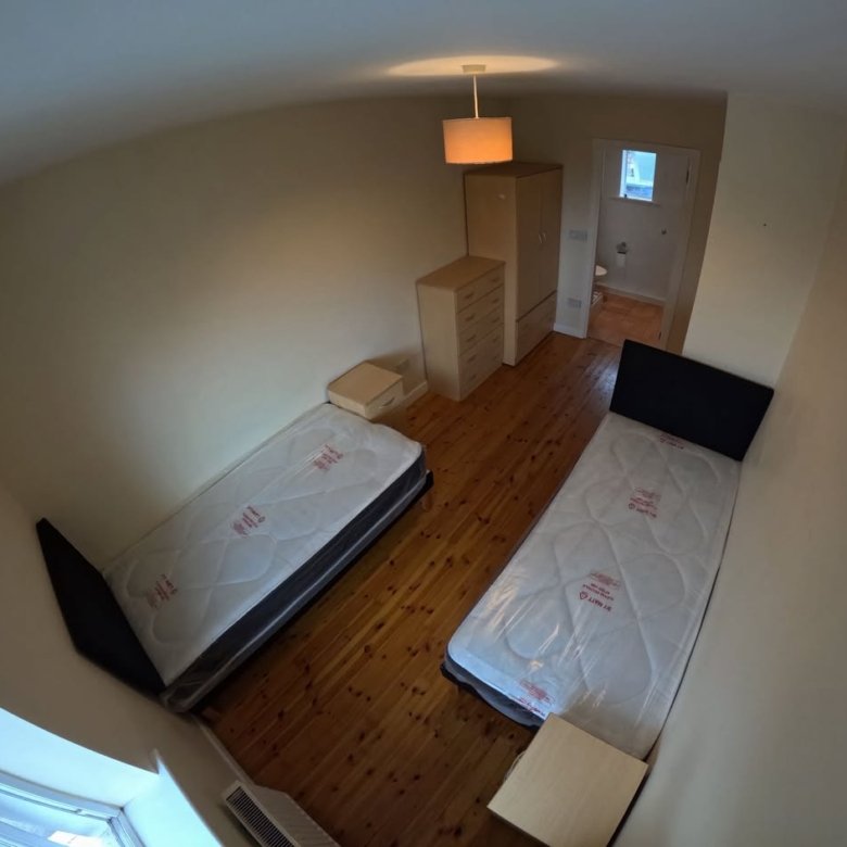 Cozy bedroom with two single beds, wardrobe, and dresser. Hardwood floors.