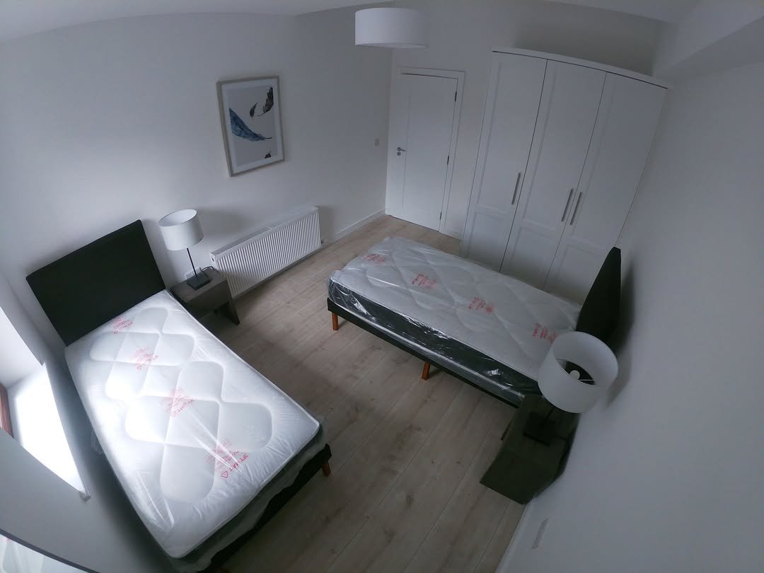 Bedroom with two single beds, wardrobe, and white walls. Modern interior design.