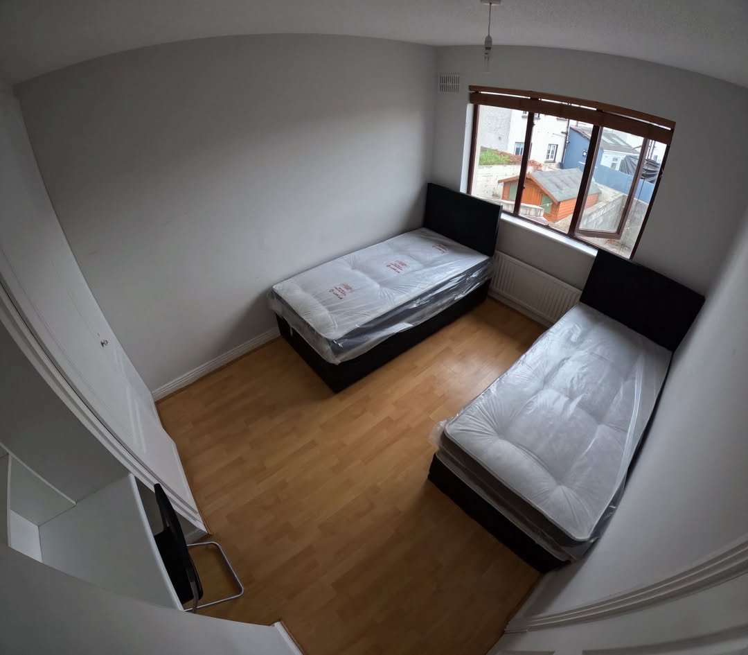 Bedroom with two single beds, wood floor, and window view.