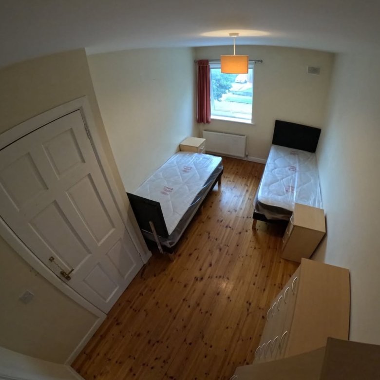 Bedroom with two single beds, wooden floors, and a white door.