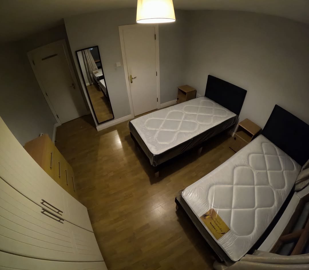 Bedroom interior with two twin beds, wardrobe, and mirror.