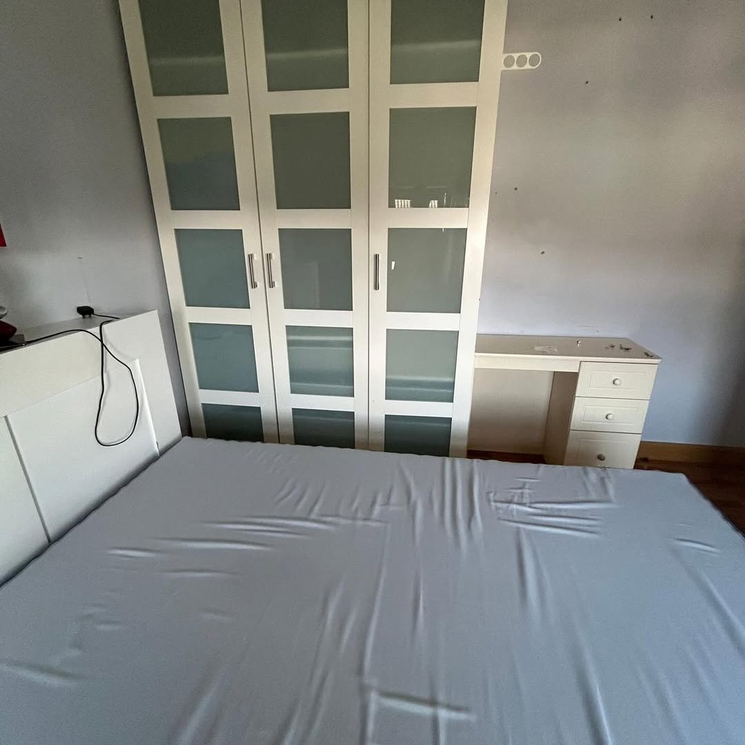 Bedroom with white bed, wardrobe, and desk. Minimalist interior design.