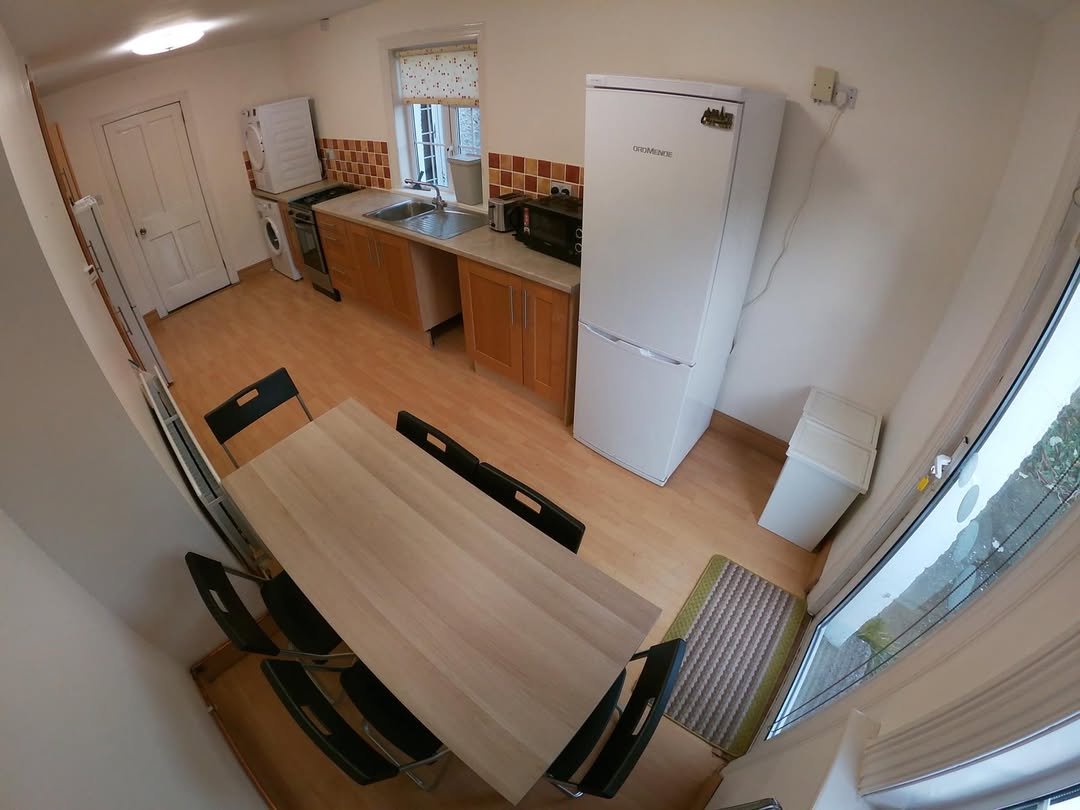 Bright kitchen with dining table, appliances, and natural light from a window and glass door.