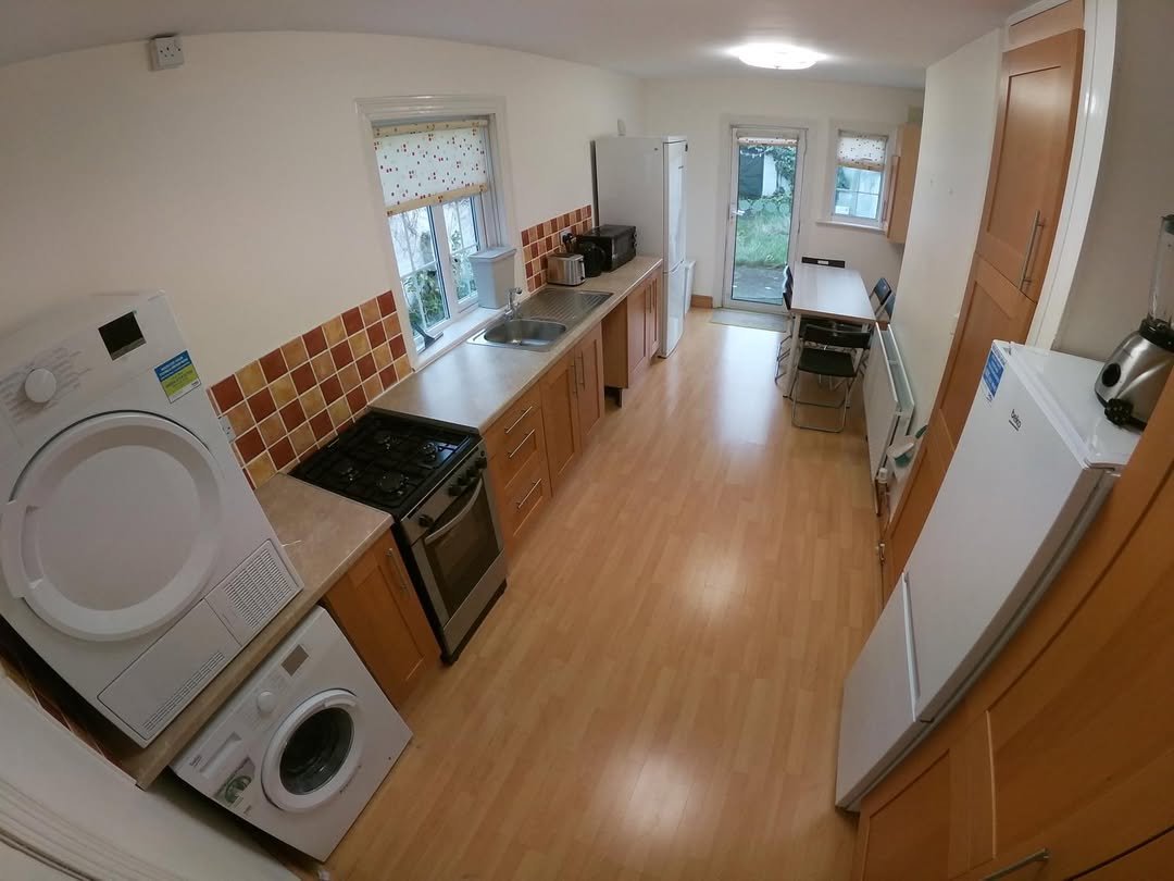 Bright kitchen with washing machine, dryer, gas stove, fridge, and dining table.