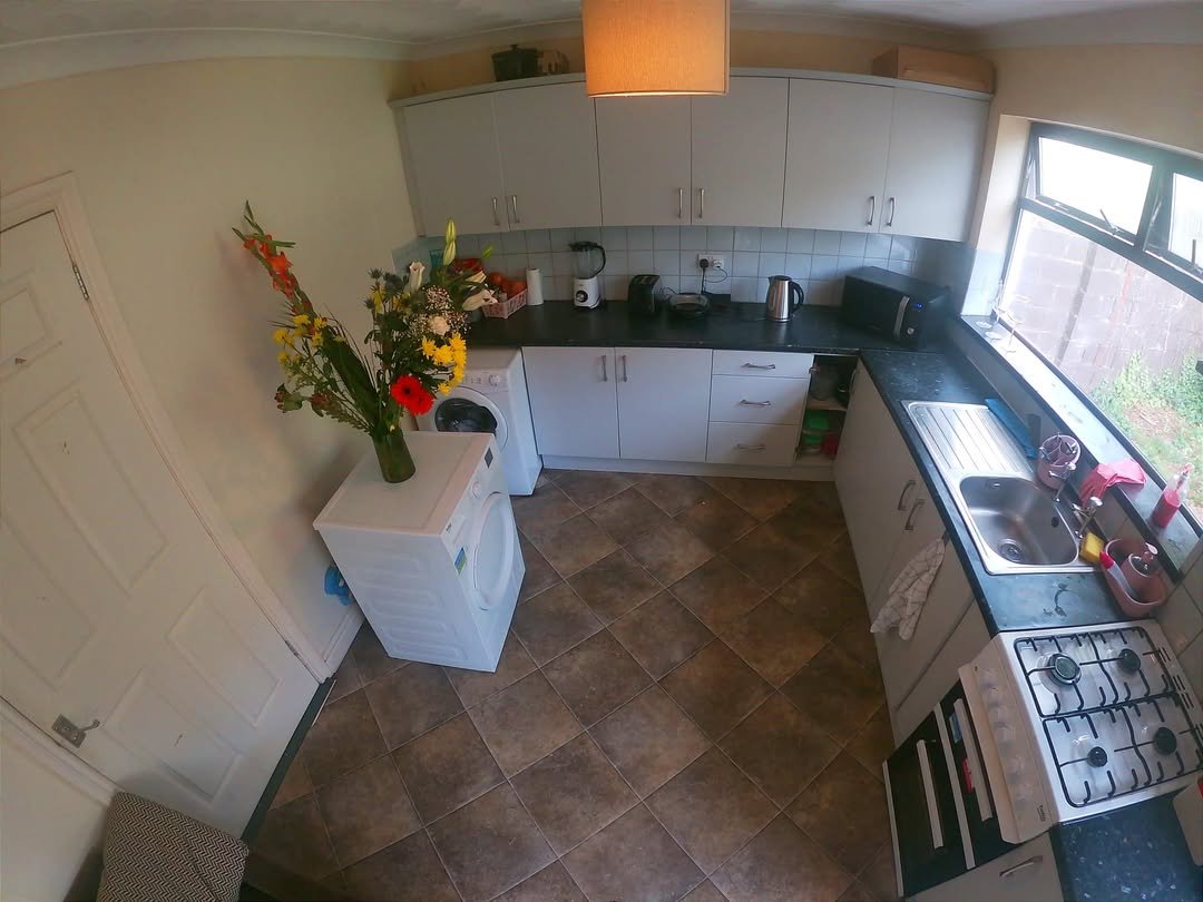 Bright kitchen with white cabinets, washing machine, and flowers.