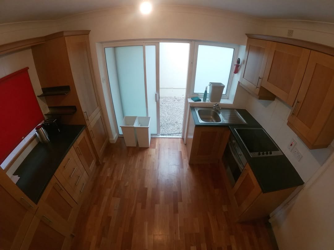 Bright kitchen with wood cabinets, black countertops, and sliding glass doors.