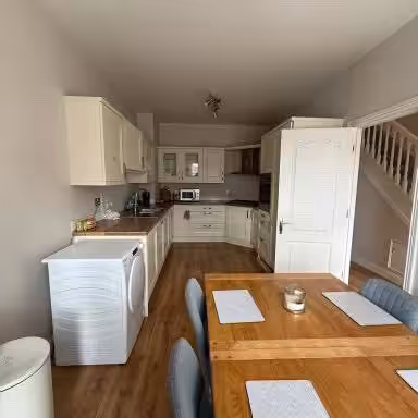 Bright kitchen with wood table, chairs, cabinets, and appliances.