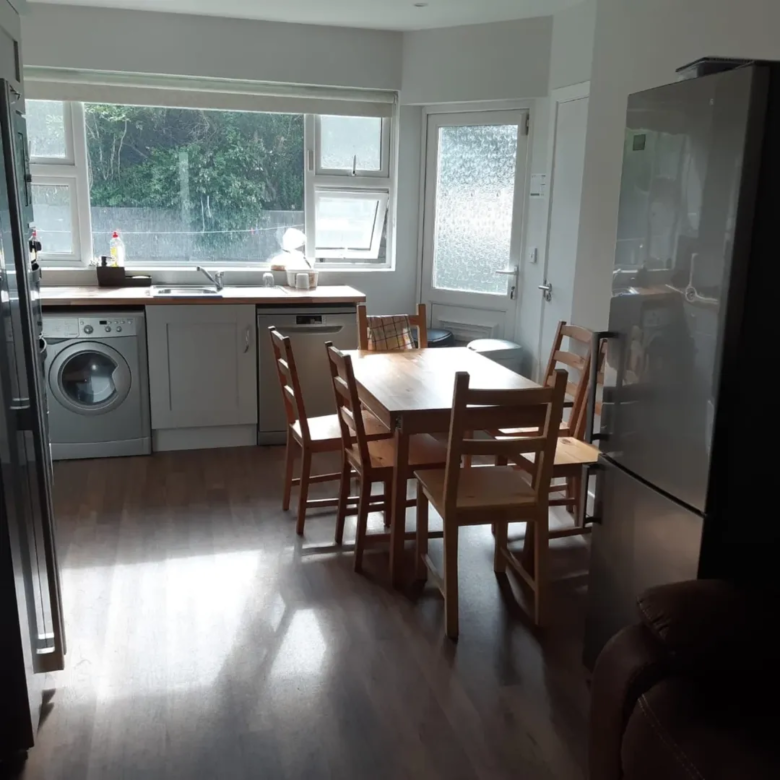 Bright kitchen with wooden dining table and chairs near window.