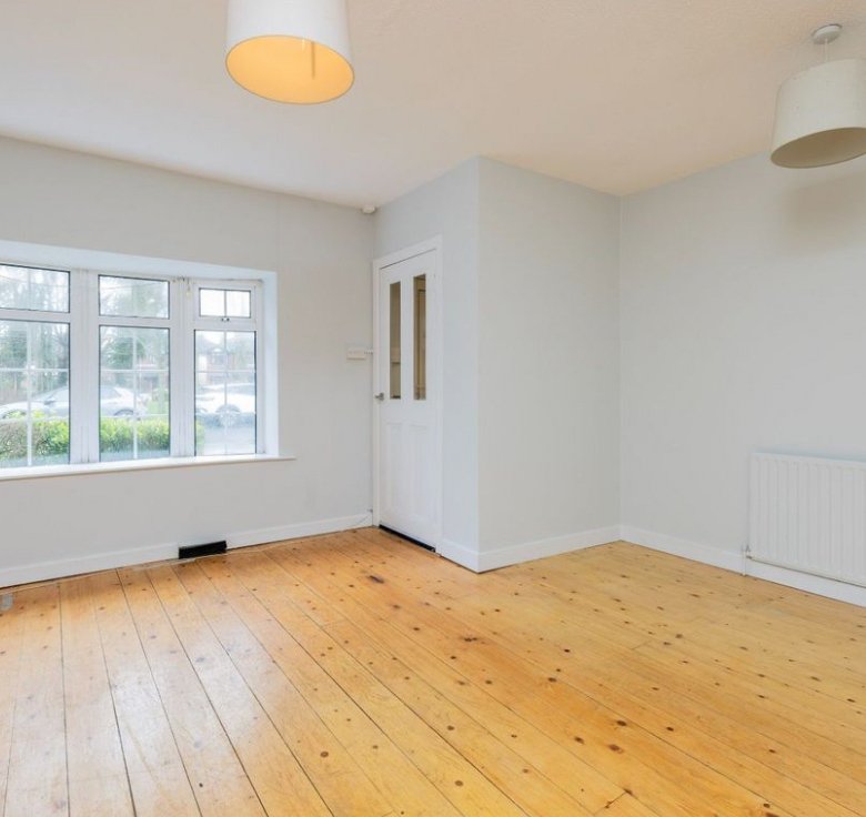 Bright room with wood floor, window, and white door. Interior design.