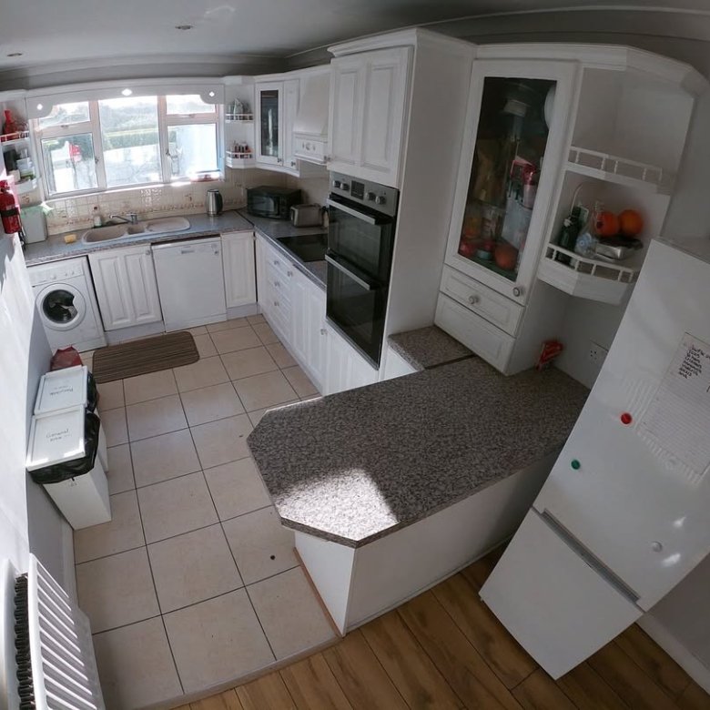 Bright kitchen with white cabinets, speckled countertop, and modern appliances.