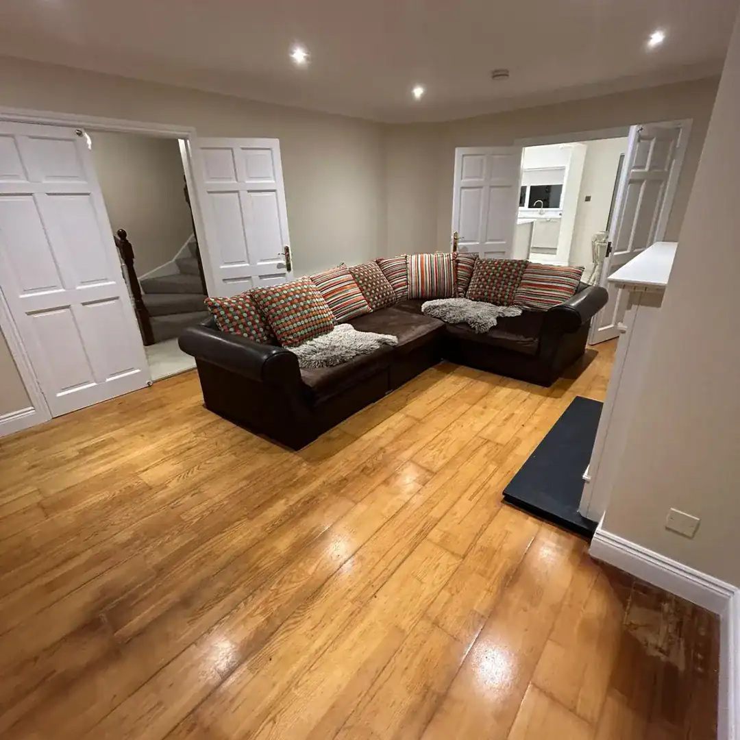 Living room with brown leather sectional sofa and hardwood floors.