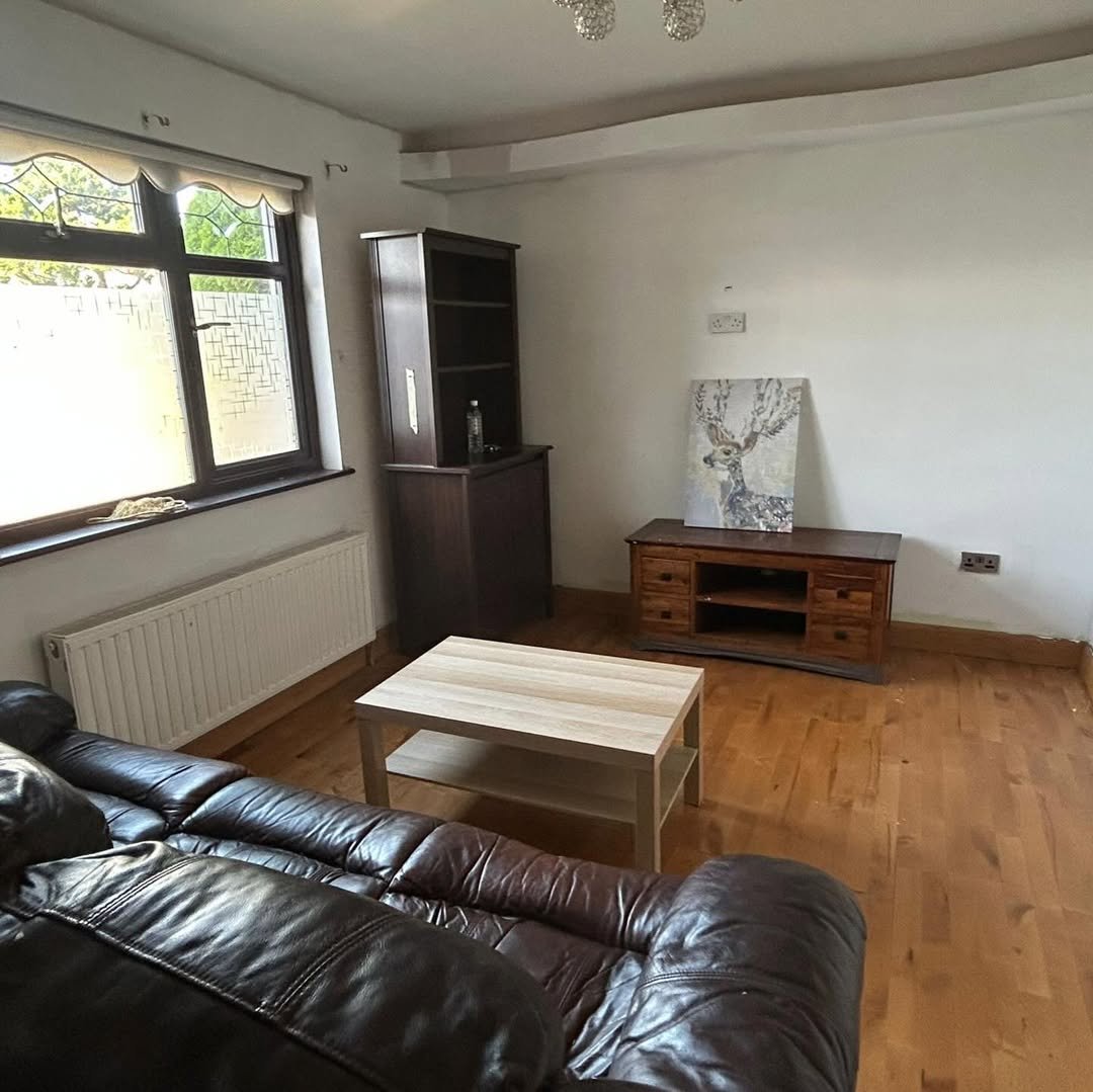 Living room with brown leather sofa, wooden furniture, and window.