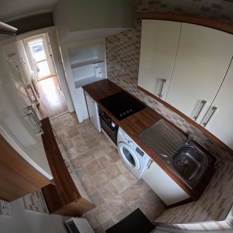 Compact kitchen with white cabinets, wood countertops, and a washing machine.