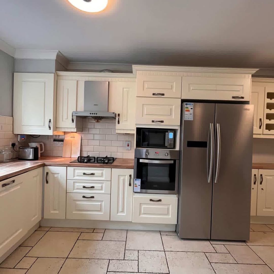 Cream kitchen with stainless steel appliances and tiled backsplash.