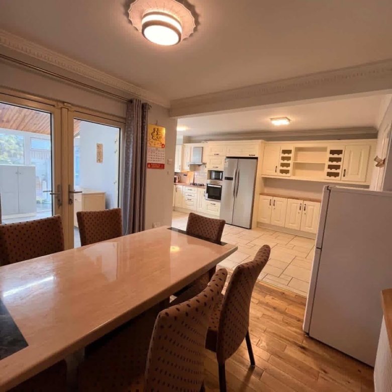 Dining area leading into a bright, cream-colored kitchen with stainless steel appliances.