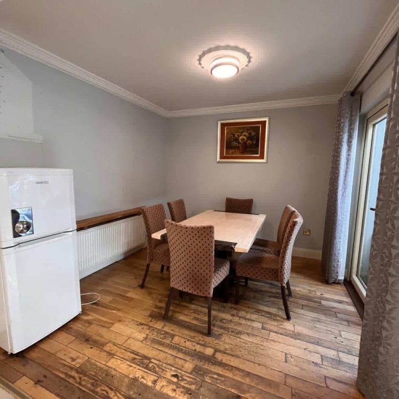 Dining room with table, chairs, fridge, and artwork on wall.