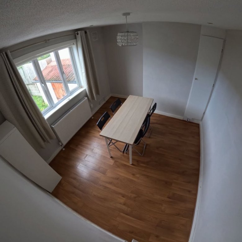 Dining room with table, chairs, window, radiator, curtains, and a light fixture.