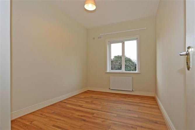 Empty room with wood flooring, window, and radiator.